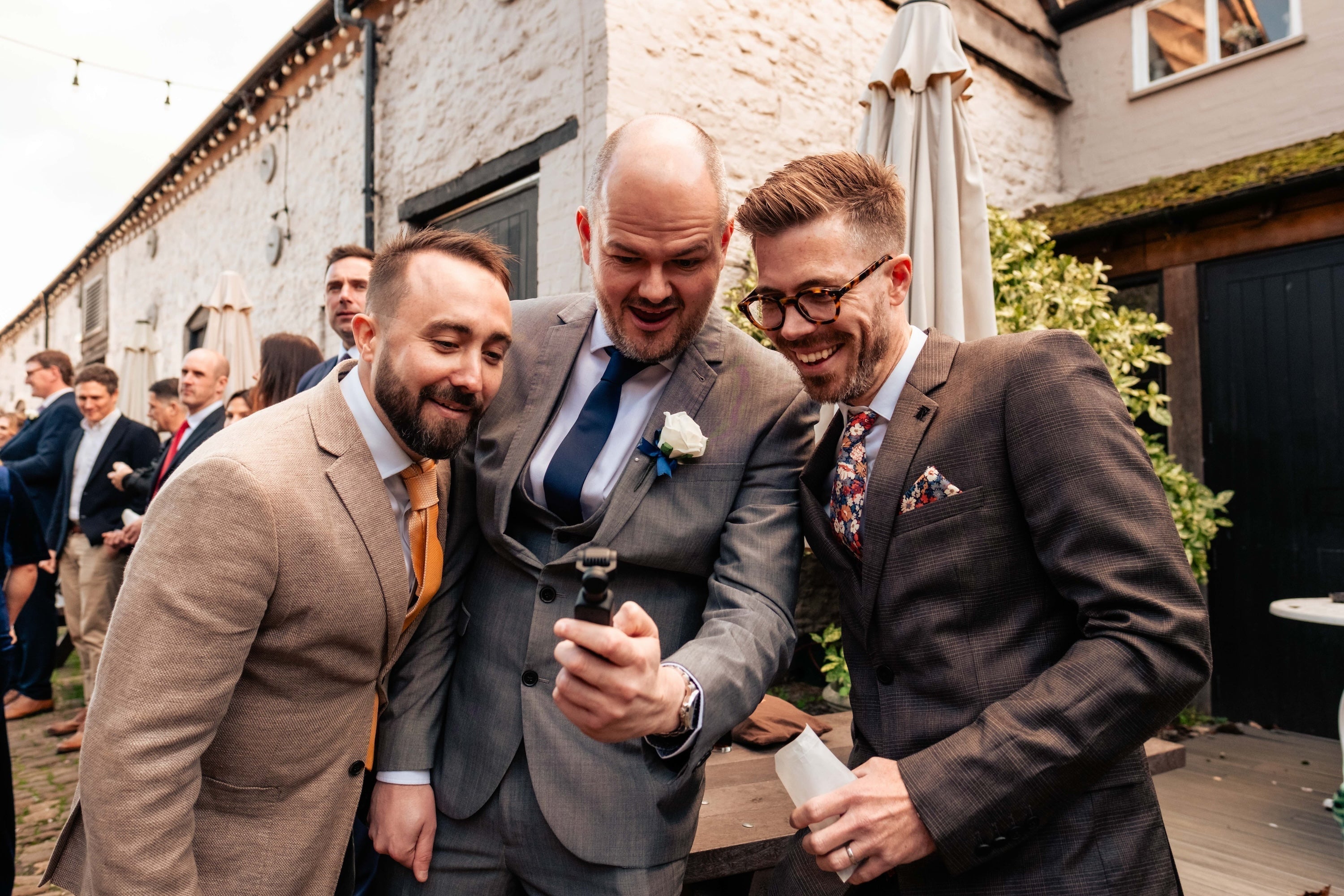 Guests filming a wedding with small handheld cameras, capturing authentic moments